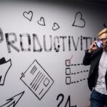 Personalized Productivity - man holding smartphone looking at productivity wall decor