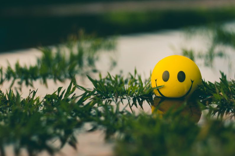 Positive Thinking - a yellow ball with a smiley face sitting in the grass